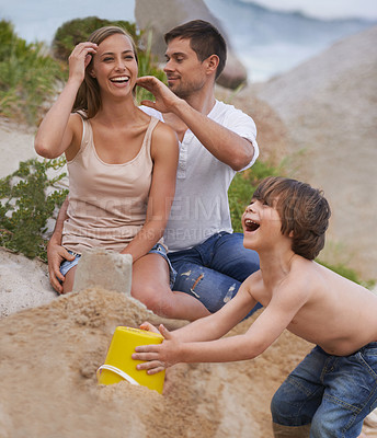 Buy stock photo Family, laughing and sand castle at beach in summer for fun, travel or holiday with love. A man, woman and excited kid playing together on vacation at sea with a toy bucket, development and happiness