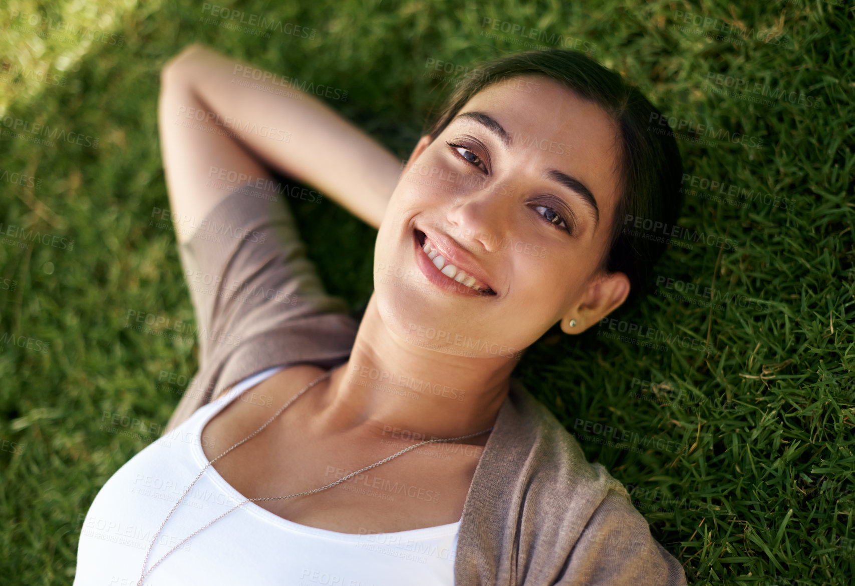 Buy stock photo Portrait, smile and relax with woman on grass outdoor in summer from above to enjoy fresh air. Face, nature and wellness with happy young person lying in field at park or garden for weekend break