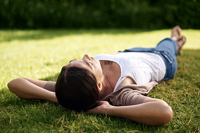 Buy stock photo High angle shot of a young woman lying on the grass