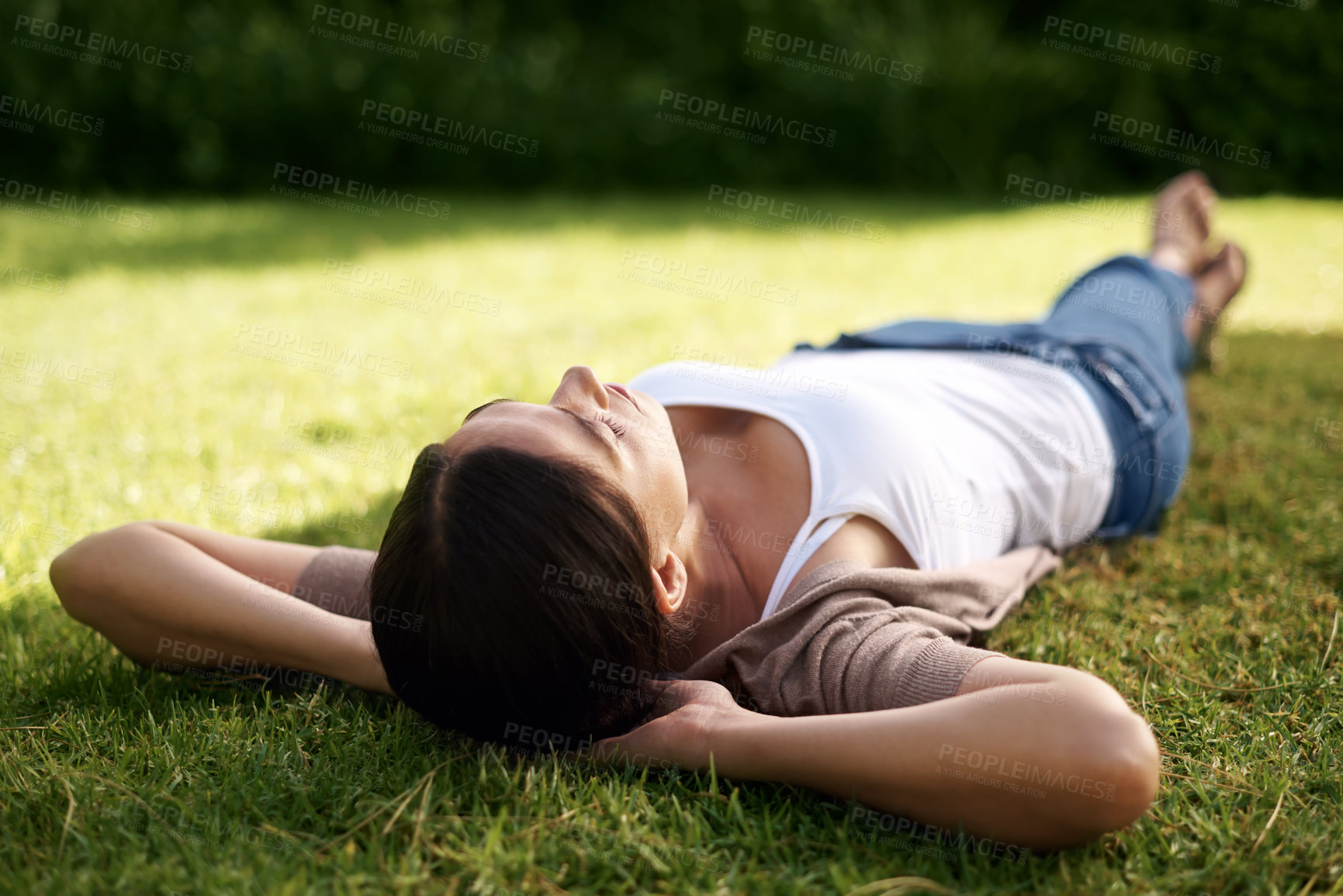 Buy stock photo High angle shot of a young woman lying on the grass