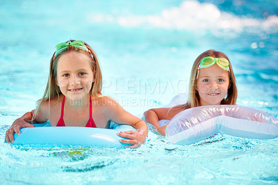 Buy stock photo Two little girls using pool inflatables while swimming