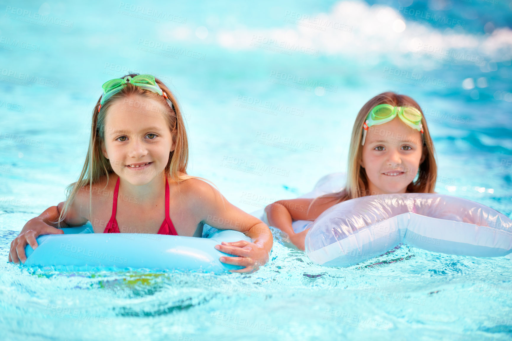 Buy stock photo Two little girls using pool inflatables while swimming