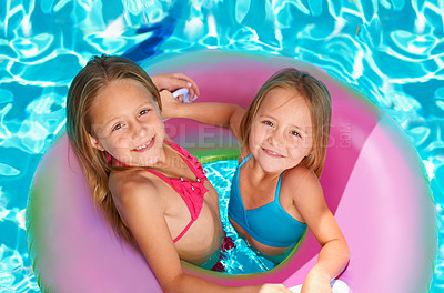 Buy stock photo Two little girls using an inflatable tube while swimming