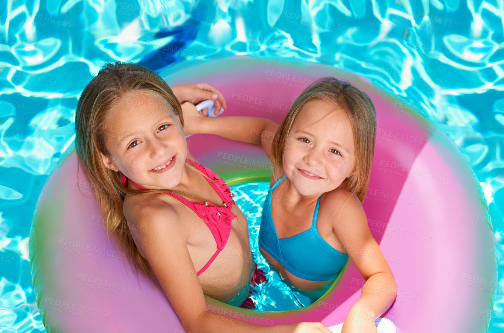 Buy stock photo Two little girls using an inflatable tube while swimming