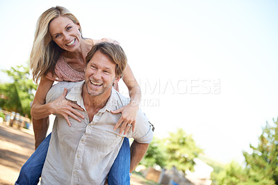 Buy stock photo Shot of a happy mature enjoying a piggyback ride in the park