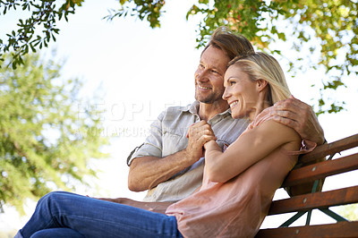 Buy stock photo Shot of a happy mature couple sitting on a bench in the park