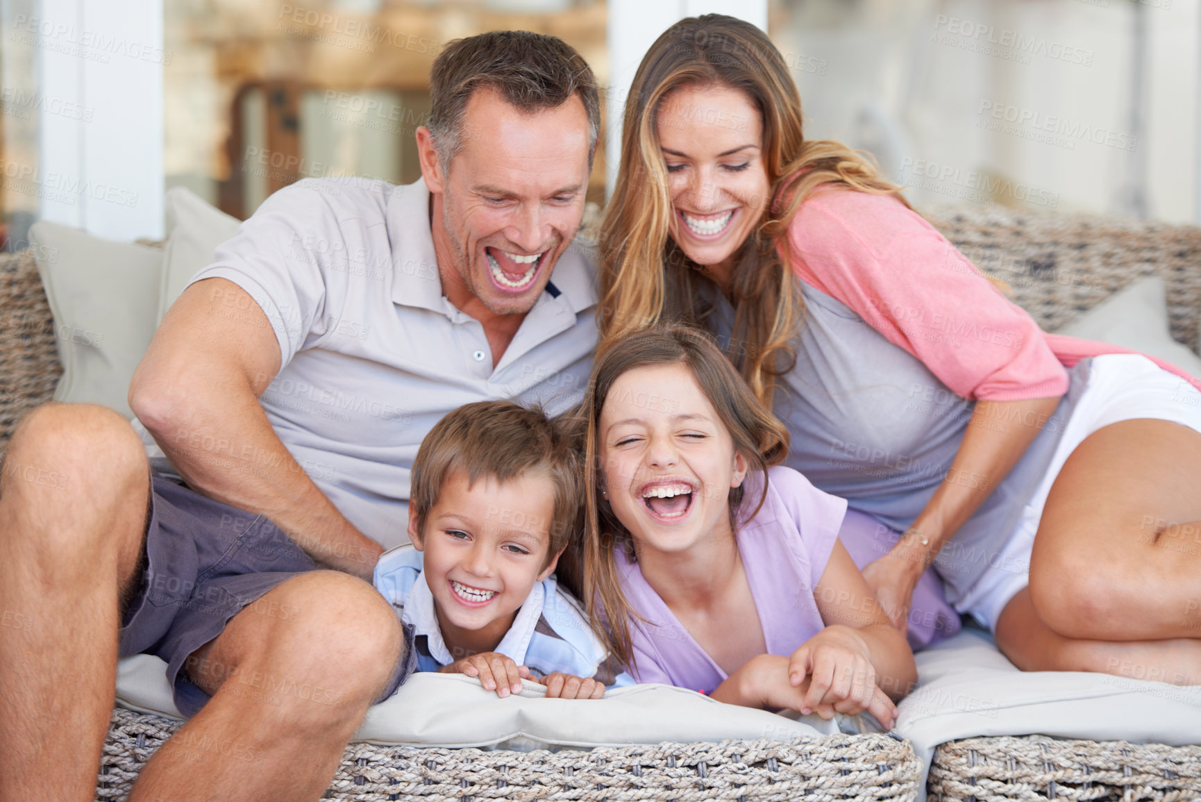 Buy stock photo Portrait of a happy young family of four sitting together on the patio