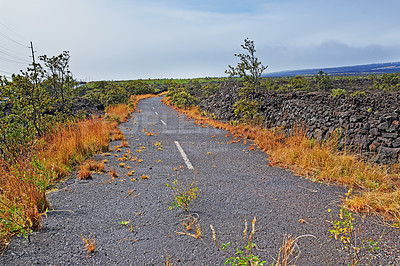 Buy stock photo Road, landscape and volcano street in nature with lava rocks, plants and grass for travel, adventure and roadtrip. Dead end, deserted path and location in Hawaii with blue sky, roadway or environment