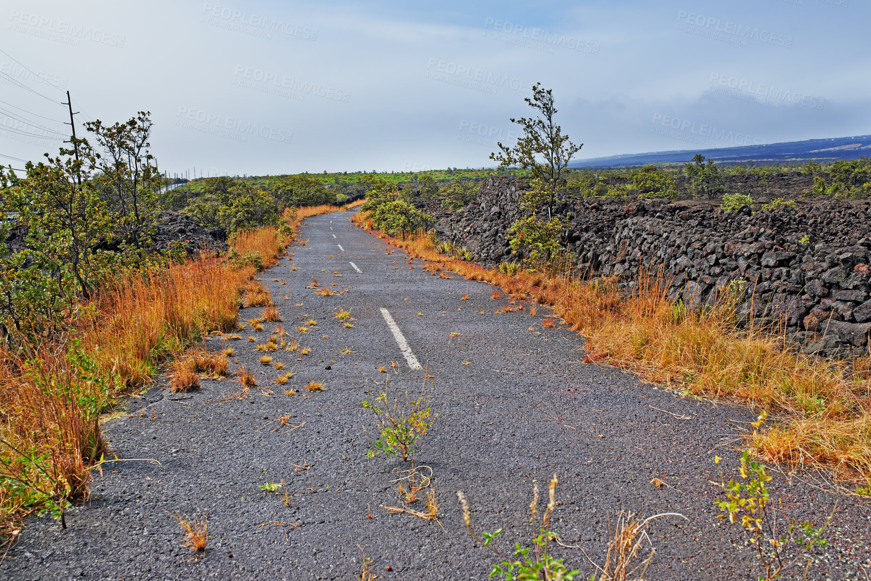 Buy stock photo Road, landscape and volcano street in nature with lava rocks, plants and grass for travel, adventure and roadtrip. Dead end, deserted path and location in Hawaii with blue sky, roadway or environment