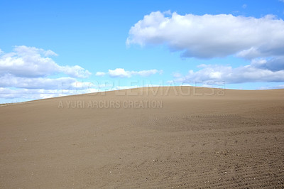 Buy stock photo Desert, landscape and clouds on blue sky background with sand in arid, barren or dry environment. Earth, nature or soil and summer horizon in hot climate or drought with banner, mockup or space