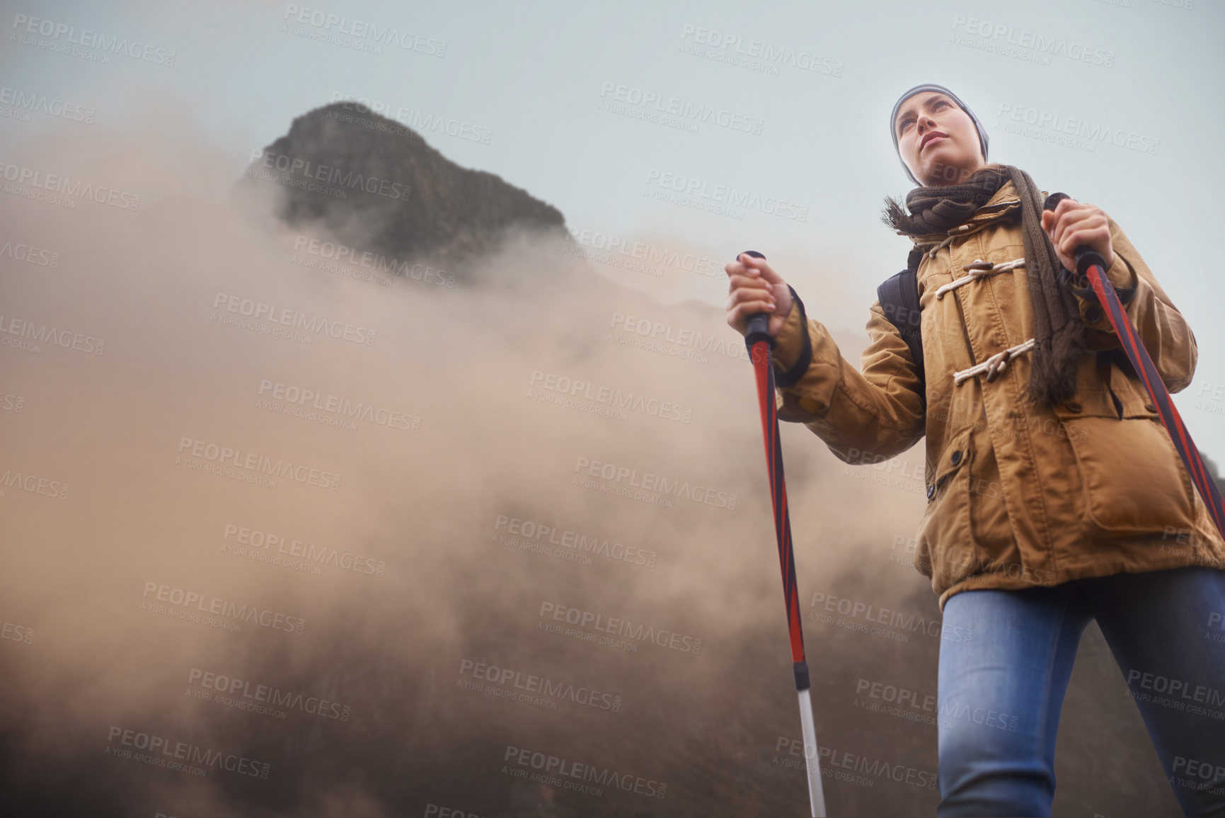 Buy stock photo Low-angle view of a young female hiker with the mountain in the background
