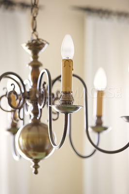 Buy stock photo Closeup of old fashioned chandelier with candle lightbulbs hanging from roof and ceiling inside at home. Texture and detail of interior design brass, victorian and antique light fixture in empty room