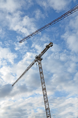 Buy stock photo Crane, construction and clouds or blue sky background for building with heavy machinery or material outdoor. Hoist in city, urban or industrial development with low angle, tools or overhead equipment