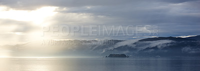 Buy stock photo Ocean, sunset and cloud on mountains in morning, cold and tropical island for vacation in nature. Blue sky, clouds and sunlight on water on beach, calm and winter weather on sustainable environment