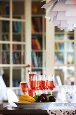 Buy stock photo Red, wine and fruit on dinner table, celebration glasses for holiday and party in home living room. Hospitality, guest preparation with alcohol beverage, bookshelf and vacation event or entertainment