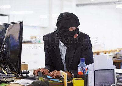 Buy stock photo Shot of a hacker dressed in a black mask hacking a computer