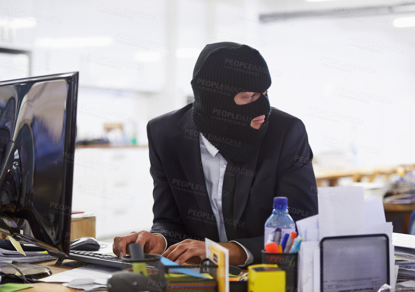 Buy stock photo Shot of a hacker dressed in a black mask hacking a computer
