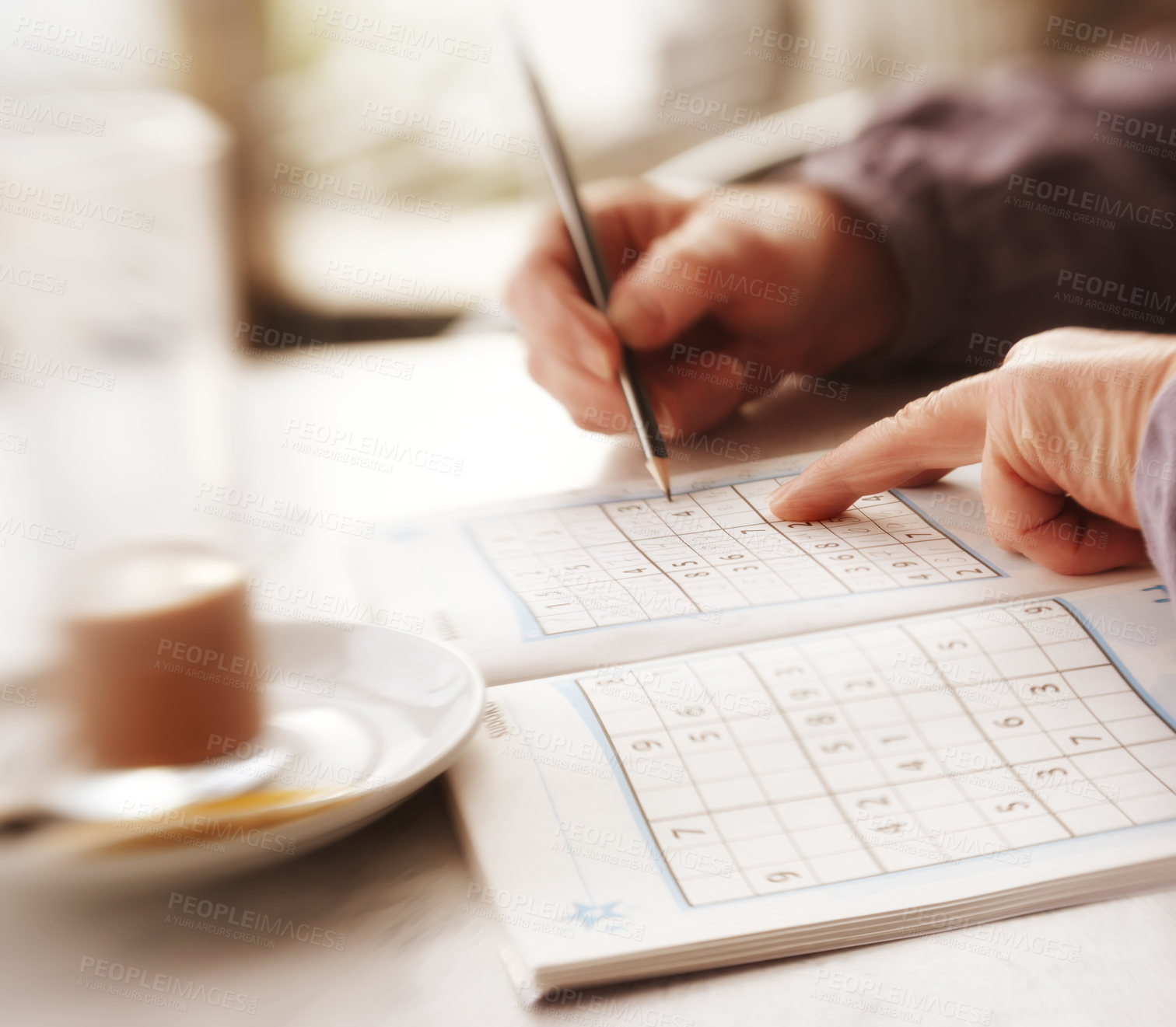 Buy stock photo Woman trying to solve Sudoku Puzzle - window, sunlight, and coffee