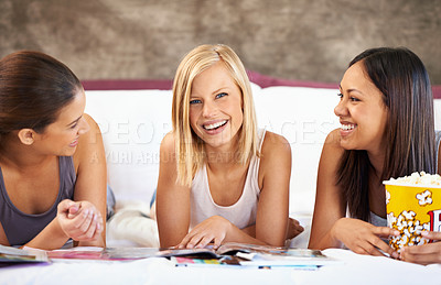 Buy stock photo Happy friends, portrait and women reading magazine in bedroom, food or eating popcorn snack together at sleepover. Smile, girls and group with journal in home, face and laugh in bed to relax in house