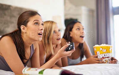 Buy stock photo Surprise, watching tv and friends eating popcorn in bedroom for streaming show, relax or amazed together at home. Television, food or group of women with shock in bed for movie, film and wow at party