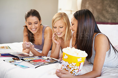 Buy stock photo Friends, popcorn and reading for sleepover, social and bedroom for bonding and excited group for snacks. Female people, together and magazines for jokes, besties and entertainment with conversation 