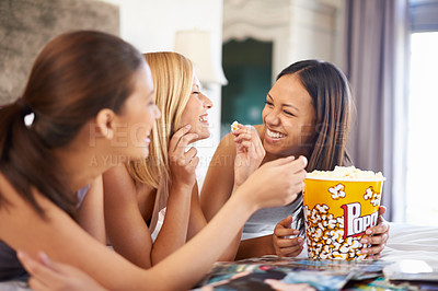 Buy stock photo Shot of three attractive young women eating popcorn on their girls' night