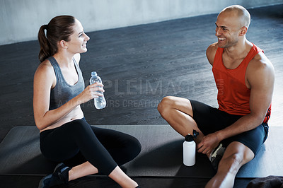 Buy stock photo Shot of a man and woman taking a break after a workout at the gym