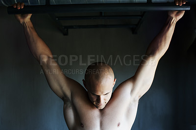 Buy stock photo Shot of a man doing pull-ups at the gym