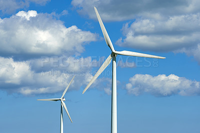 Buy stock photo Wind turbines and environmental infrastructure isolated against blue sky with copy space on empty energy farm. Propellers converting sustainable energy into electric power in remote and rural area