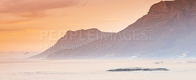 Buy stock photo Ocean, sunset and mist on mountains by blue sky and sustainable environment for vacation in nature. Landscape, sea and sunlight on water on beach, calm and cape town for tourist destination or travel