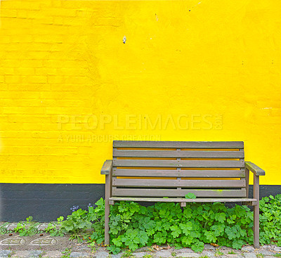 Buy stock photo A single wooden bench against a bright yellow wall