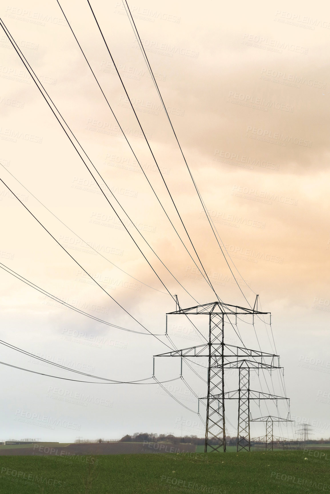 Buy stock photo View of electricity cables running over a field against a cloudy sky outside. Group of power lines and pylons providing rural and remote areas with power. Electrical transmission and distribution 