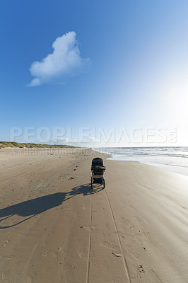 Buy stock photo Stroller, sand and blue sky with cloud by beach for travel, vacation or holiday in summer. Baby pram, nature and ocean by seashore for tropical weekend trip on outdoor island destination in Cape town