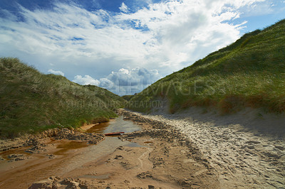 Buy stock photo River, nature and landscape of water stream, green hill and beach with texture and mud in environment for ecosystem. Moving liquid, sea or lake with natural resource, element and landscape outdoor