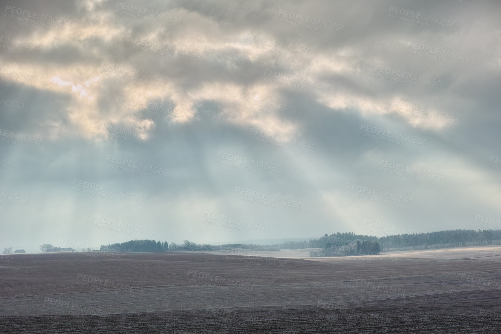 Buy stock photo Sunlight breaking through the clouds onto a deserted field