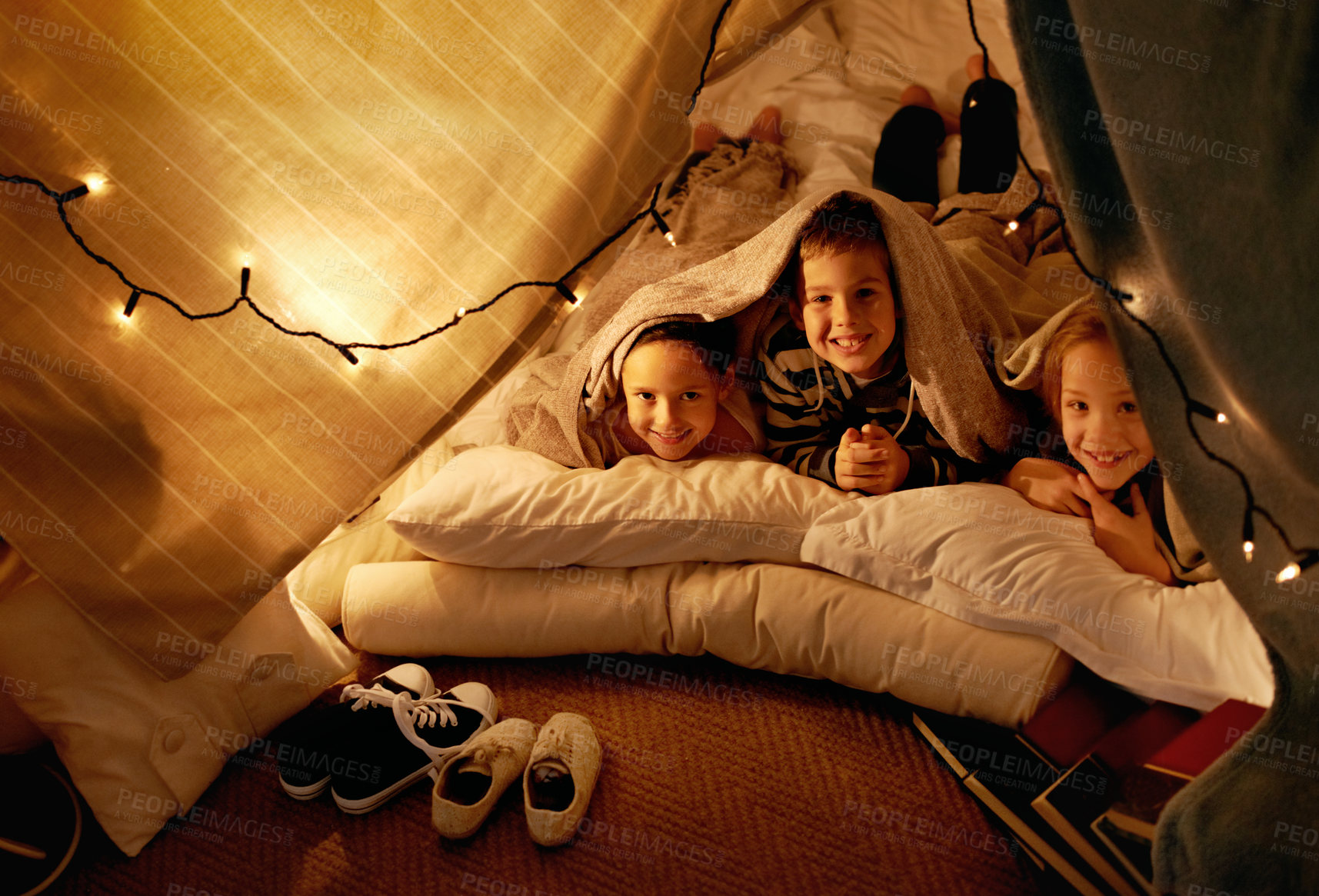 Buy stock photo Children, smile and playing in blanket fort with portrait for fantasy, bonding and string lights at night. Friends, kids and face or happy for pajama party, sleepover and pillow tent with lighting 