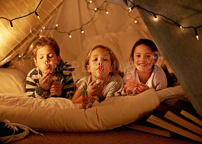 Buy stock photo Children, fort and portrait of siblings in a bed with fun, toy and bonding while blowing bubbles at home together. Family, night and kids in a bedroom for evening games, playing or indoor camping