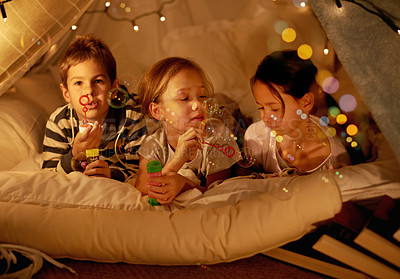 Buy stock photo Shot of three young children in a blanket fort blowing bubbles