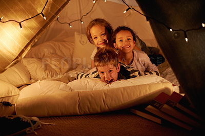 Buy stock photo Children, happy and playing in blanket fort with portrait for fantasy, bonding and string lights at night. Friends, kids and face with smile for pajama party, sleepover and pillow tent with lighting 
