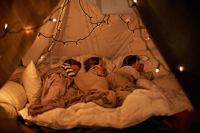Buy stock photo Shot of three young children sleeping in blanket tent
