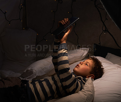Buy stock photo Child, tablet and watch in tent at night for movies, film or cartoon on holiday or vacation in dark room. Boy or kid by fairy lights, pillows and relax at home on digital technology or reading ebook