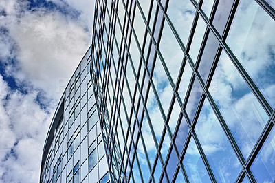 Buy stock photo Low angle, architecture and building with glass windows in city for business, office and commercial property with sky. Clouds, construction and real estate for hotel, accommodation and skyscraper