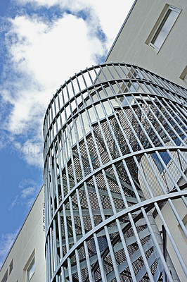 Buy stock photo A spiral staircase on the outside of a building. Grey steel spiral stairs built on the side of modern industrial office building. Low angle of a metal circular fire escape staircase with railings
