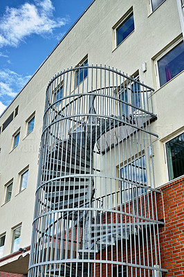 Buy stock photo A spiral staircase running down the side of a building. Emergency exit fire escape. Backyard escape stairs. Caged emergency ladder for the safety of the residents in case of a fire or fire drill