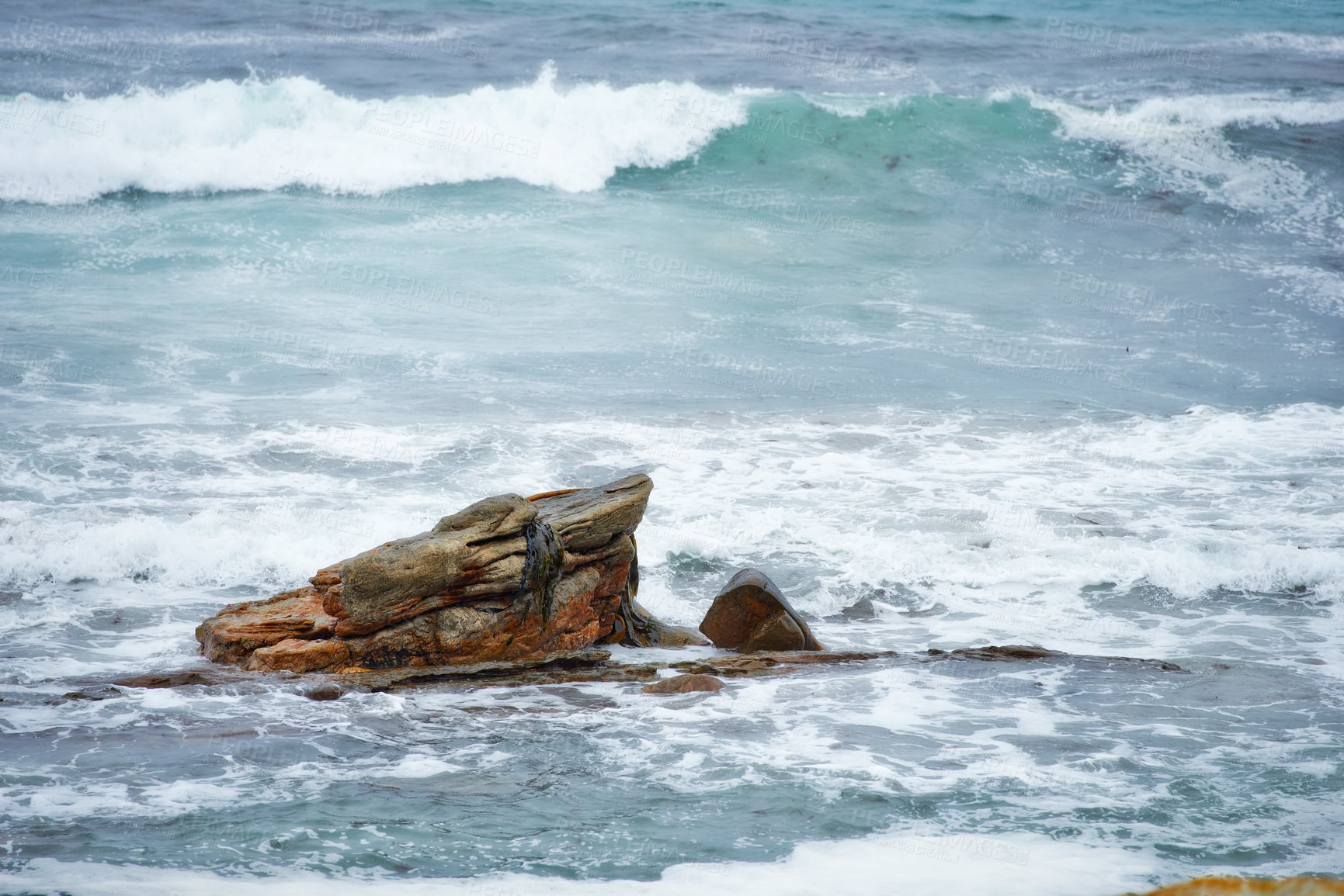 Buy stock photo One rock with waves crashing around it. Rock formation in calm peaceful blue ocean. Waves moving in and out by the seaside. Rocky shoreline with clear water. Holiday location for travel destination