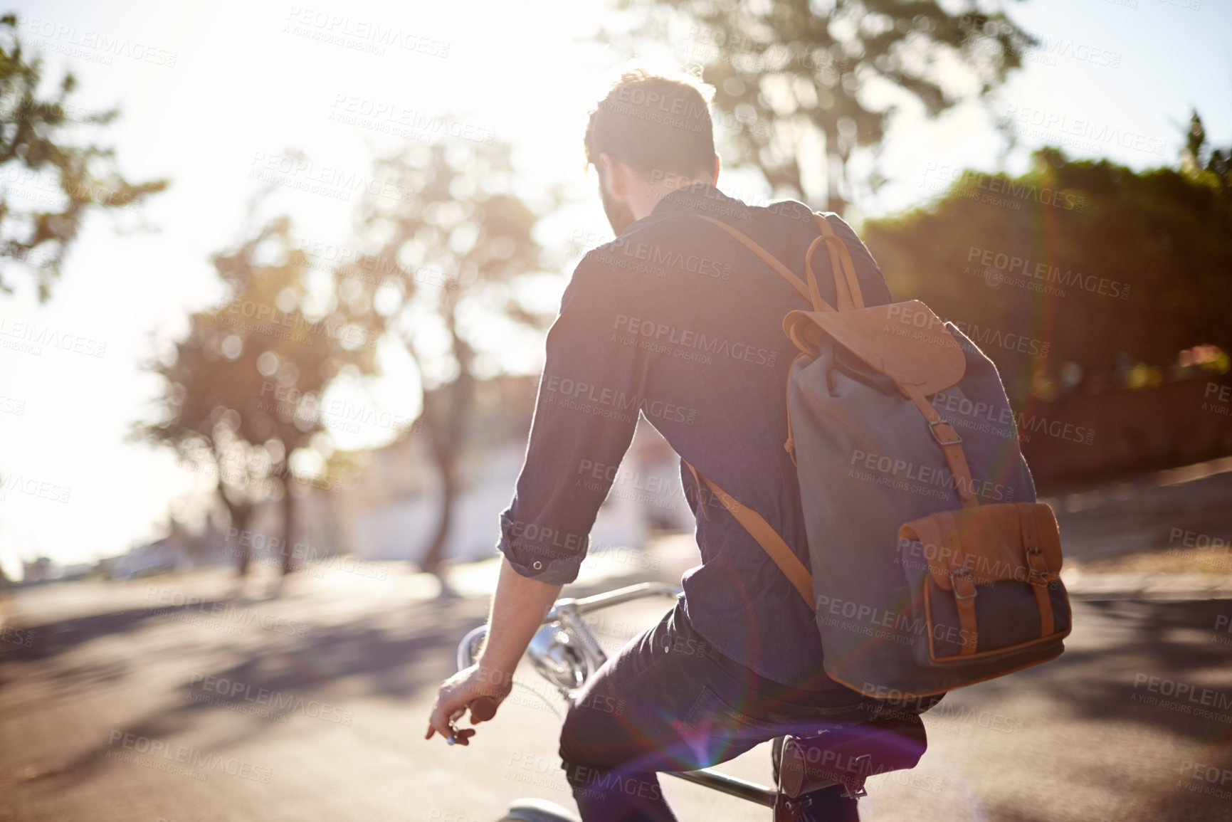 Buy stock photo Bicycle, travel and back of man in street with lens flare for exercise, commute and cycling in morning. Transport, city and male cyclist on bike for eco friendly traveling, carbon neutral and journey