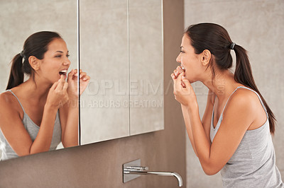 Buy stock photo A beautiful young woman flossing while standing in her bathroom