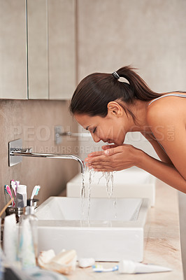 Buy stock photo A beautiful young woman washing her face in her bathroom