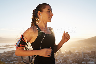 Buy stock photo Woman, running and sunset with earphones for workout, exercise or cardio training on mountain. Active female person or runner listening to music, podcast or audio for energy, health and wellness