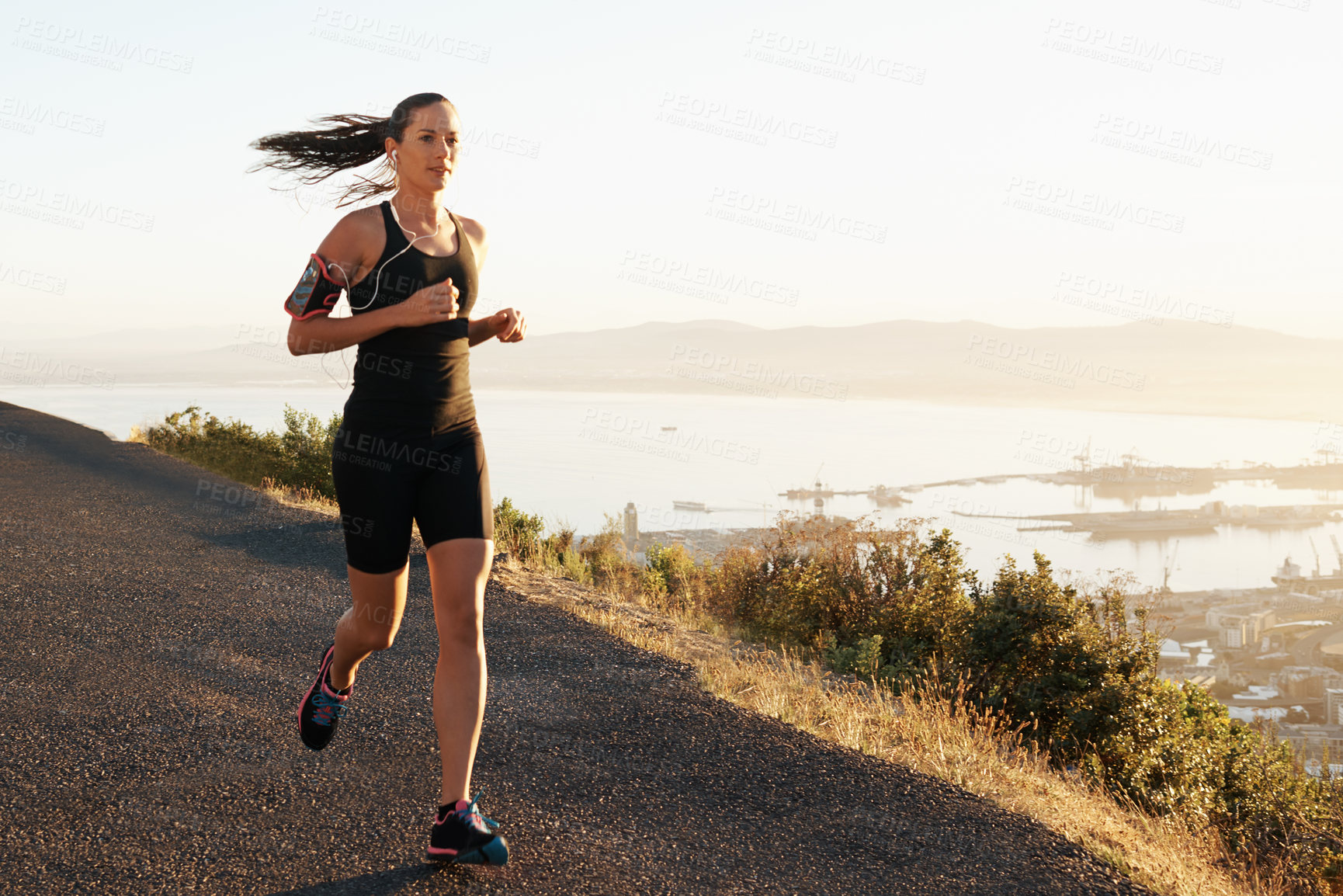 Buy stock photo Athlete, woman and running in road with music for sport, exercise or fitness for competition or marathon in nature. Runner, person and workout with wellness, seaside or earphones for cardio in Mexico
